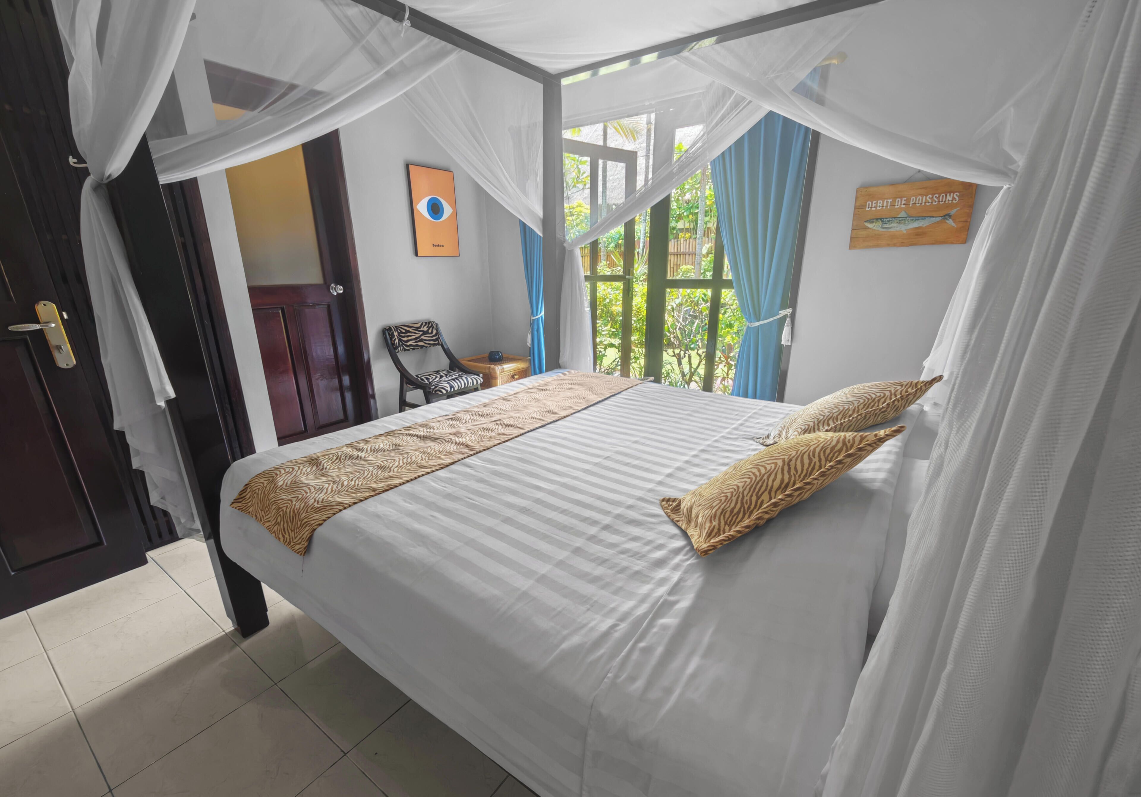 Un dormitorio con cama, una silla, una mesita y una ventana con cortinas.