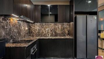 Una cucina moderna con mobili in legno scuro, una schiena di marmo e elettrodomestici in acciaio inossidabile.