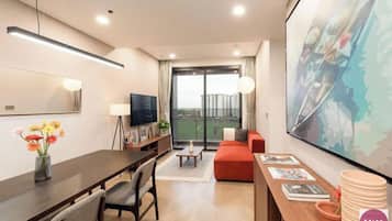 A modern hotel room with a dining area, a sofa, a TV, and a large window with a view.