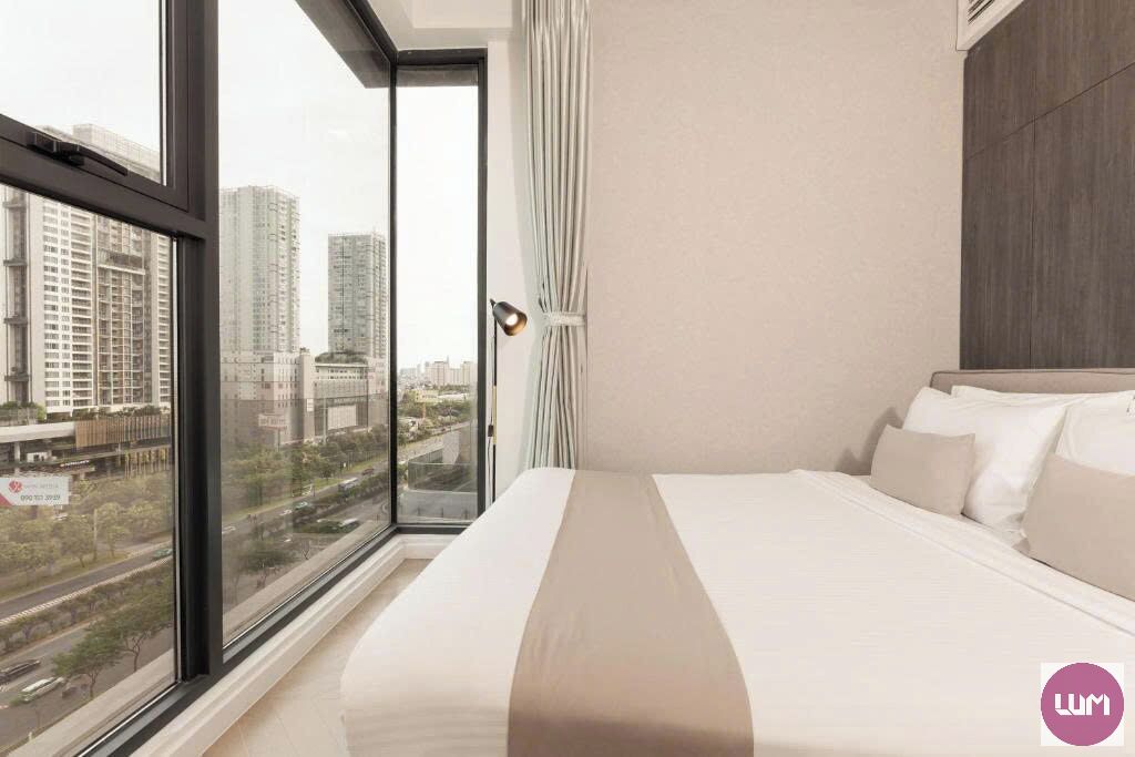 Habitación de hotel con un ventanal amplio que ofrece vistas a la ciudad, cama con ropa blanca y diseño moderno.