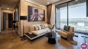 A modern living room with a sofa, a coffee table, and a large window offering a city view.