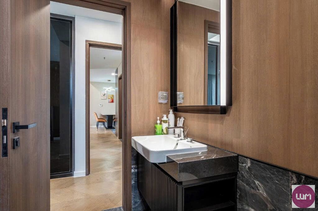 A modern bathroom with a large mirror, a white sink, and a black vanity.