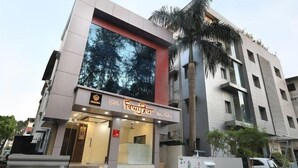 A modern building with a large glass facade reflecting trees. - Vishnupriya Grand (Kolhapur)