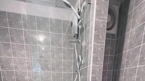 A bathroom with a shower, toilet, and a towel rack. - We Resident (Bangkok)