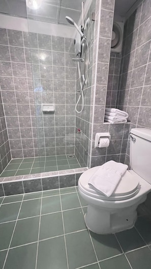 Un baño con ducha, inodoro y un perchero para toallas.