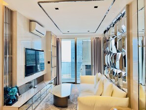 Een moderne woonkamer met een flatscreen televisie, een bank, een bijzettafeltje en een decoratieve spiegelwand.