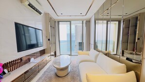 Una habitación de hotel moderna con una televisión de pantalla plana, un sofá, una mesa de centro y un ventanal con vistas a la ciudad.