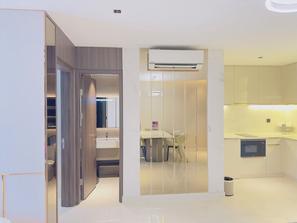 A modern kitchen with a built-in air conditioner, a dining area with a table and chairs, and a separate bathroom with a sink and mirror.