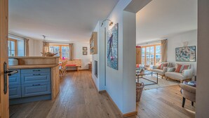 A spacious living area with a wooden floor, a dining area with a bench, and a kitchen with blue cabinets. - Exclusive chalet in the Kitzbühel Alps (Jochberg)