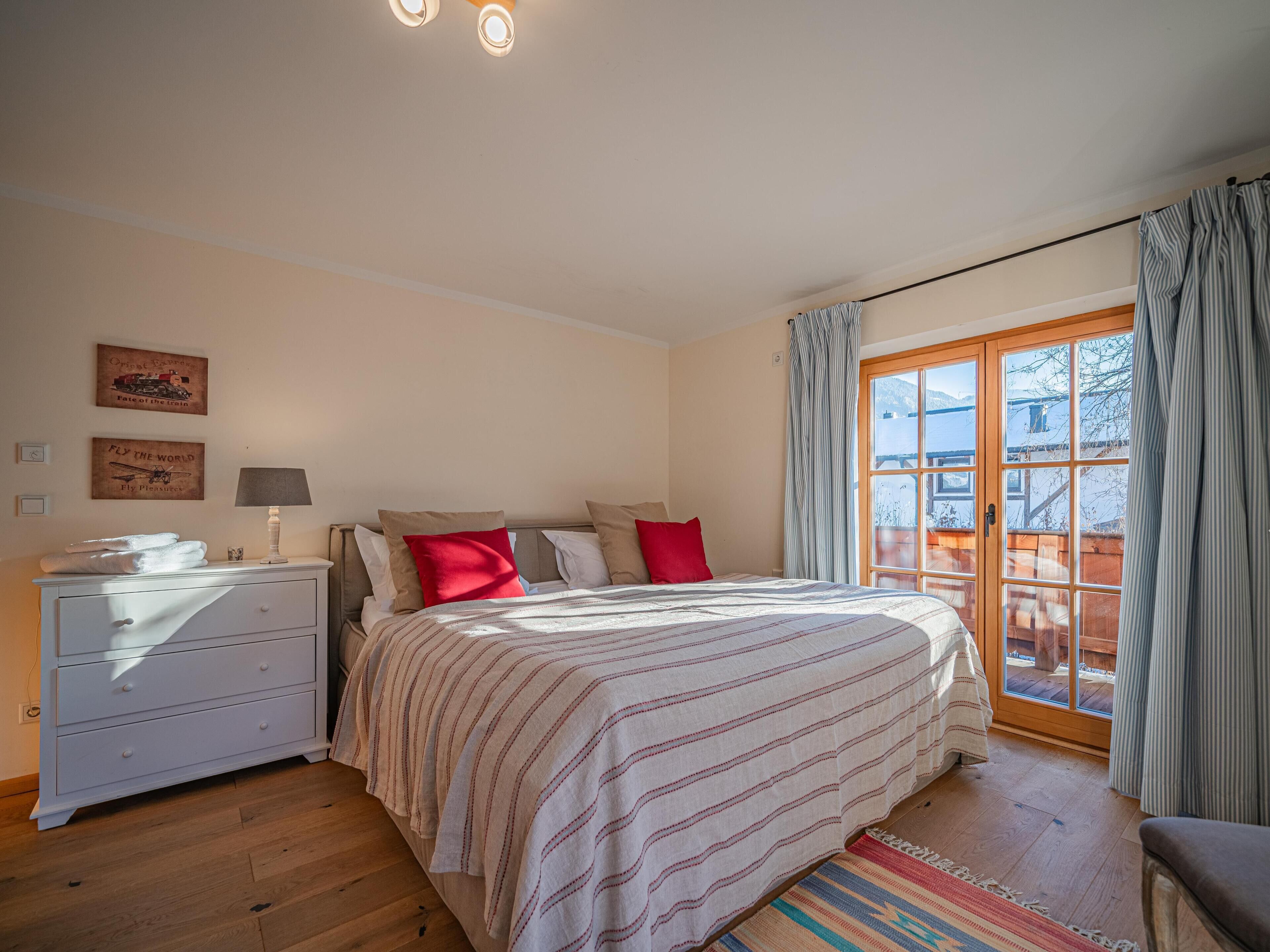 Un dormitorio con cama, mesita de noche, cómoda y ventana con cortinas.