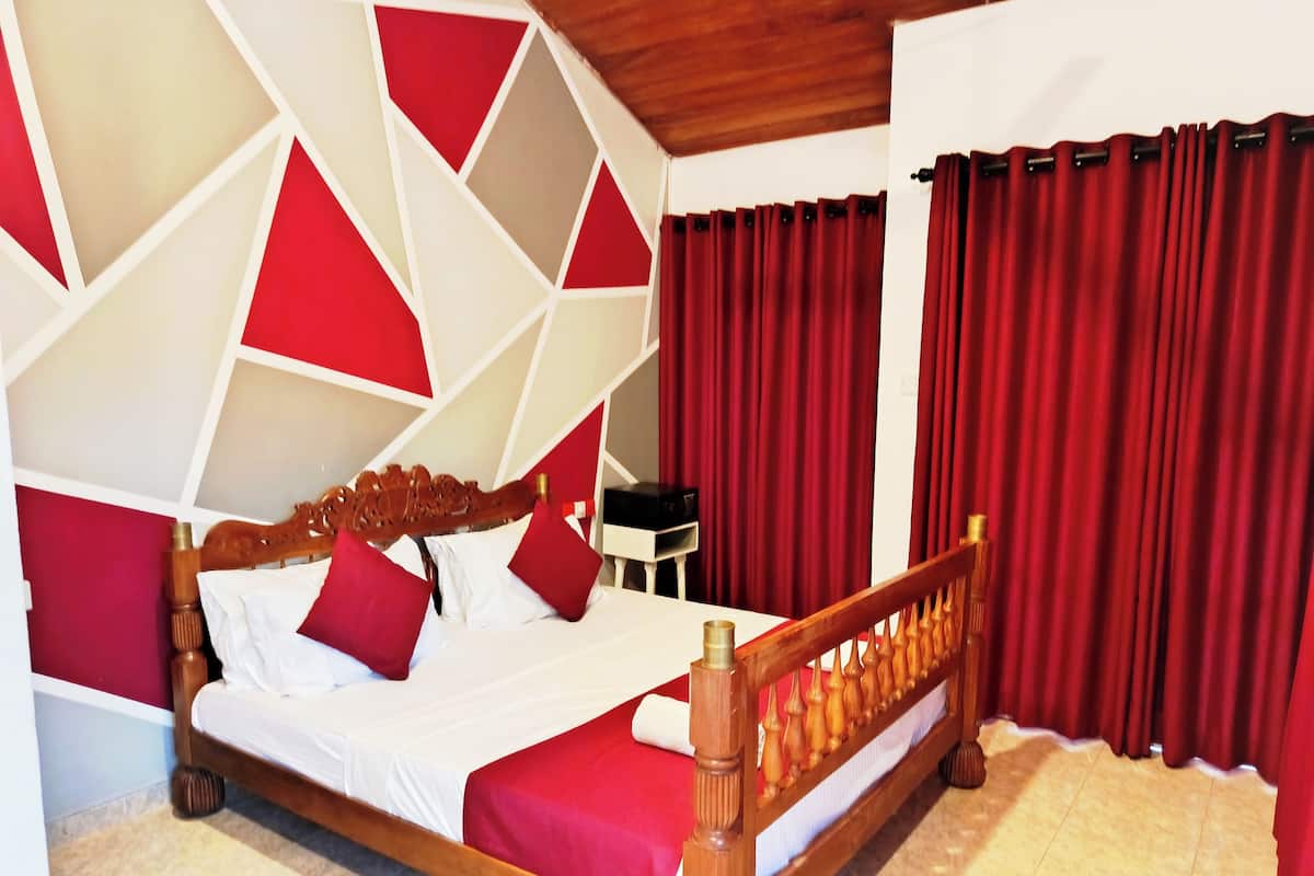 Un letto con struttura in legno e biancheria rossa, un motivo geometrico sulla parete e tende rosse.