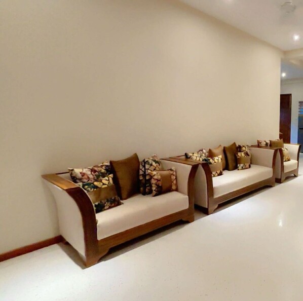 A modern living room with a long, low-profile sofa set against a plain wall. - Canberra Holidays - Mirissa (Mirissa)