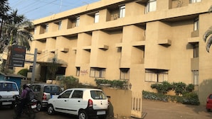 A multi-story hotel with a flat facade, several balconies, and a sign indicating it offers accommodation and a banquet hall. - Hotel Anugraha Deluxe (Kolhapur)