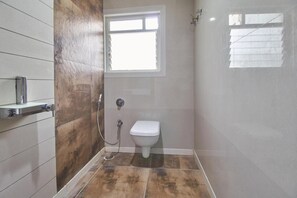 A bathroom with a shower, toilet, and a window. - Hotel Anugraha Deluxe (Kolhapur)