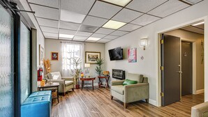 A spacious living area with a wooden floor, a blue ottoman, a sofa, a coffee table, and a TV mounted on the wall. - 8 Mi to Tarpon Springs Sponge Docks: Gem w/ Games (Odessa)