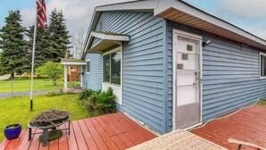 Una casa con revestimiento azul, un deck rojo y un pequeño jardín.
