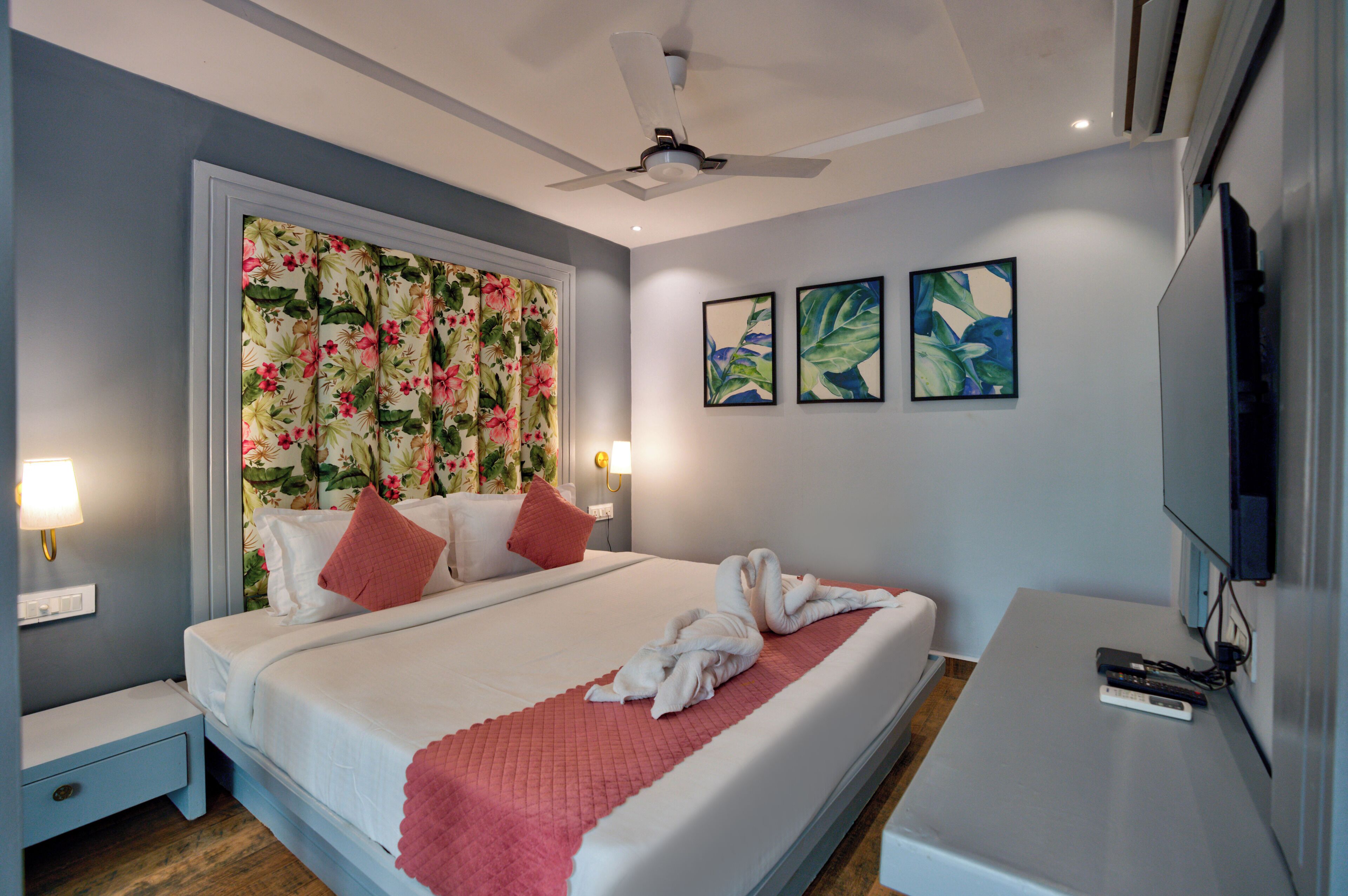 A hotel room with a bed, a nightstand, a TV, and a ceiling fan.