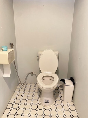 A small bathroom with a toilet, a hand dryer, and a trash bin. - Khaopoon Camping (Kanchanaburi)