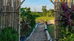 A bamboo gate with a wooden sign, leading to a gravel path surrounded by greenery. - Khaopoon Camping (Kanchanaburi)