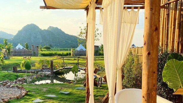 A serene outdoor setting with a wooden pergola, a white bathtub, and a small pond. - Khaopoon Camping (Kanchanaburi)