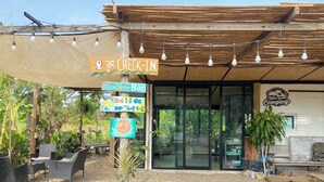 A cafe bar with outdoor seating, a check-in sign, and a sign for tents 13 and 4-6. - Khaopoon Camping (Kanchanaburi)