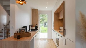 A modern kitchen with a wooden island, white cabinets, and a hanging light fixture. - Ty Mezou - Pretty house on the Gr34 near to the se (Porspoder)