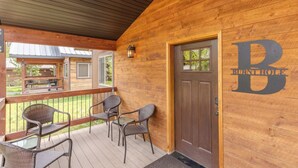 A wooden exterior of a building with a porch, a door marked "BURNTHOLE HOTEL," and outdoor seating. - Burnt Hole (West Yellowstone)