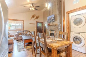 Una sala de estar acogedora con chimenea, un comedor con muebles de madera y un cuarto de lavado con lavadora y secadora frontales.