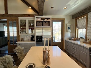 A modern kitchen with a central island, built-in cabinets, and a large window.