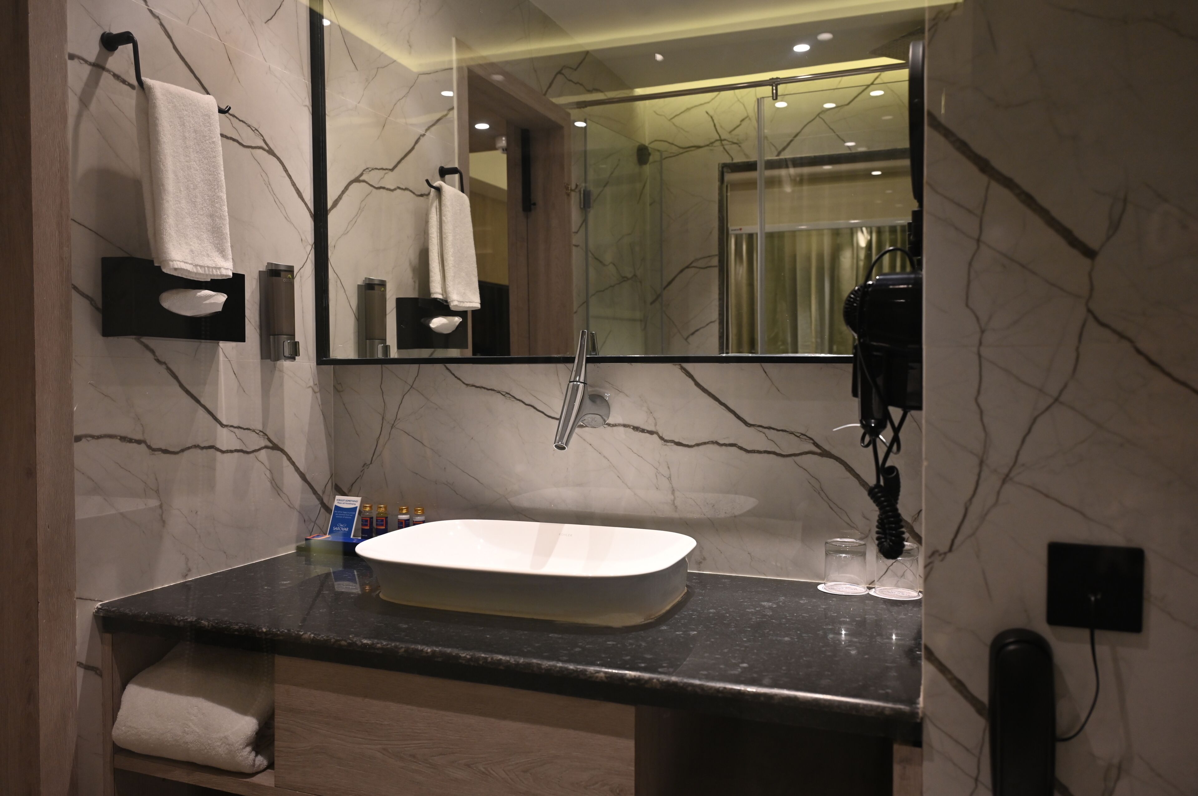 A bathroom with a marble sink, a large mirror, and a towel rack.