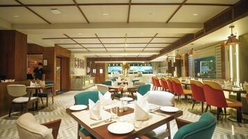 A restaurant with tables set for dining, a bar area, and a view of the kitchen.