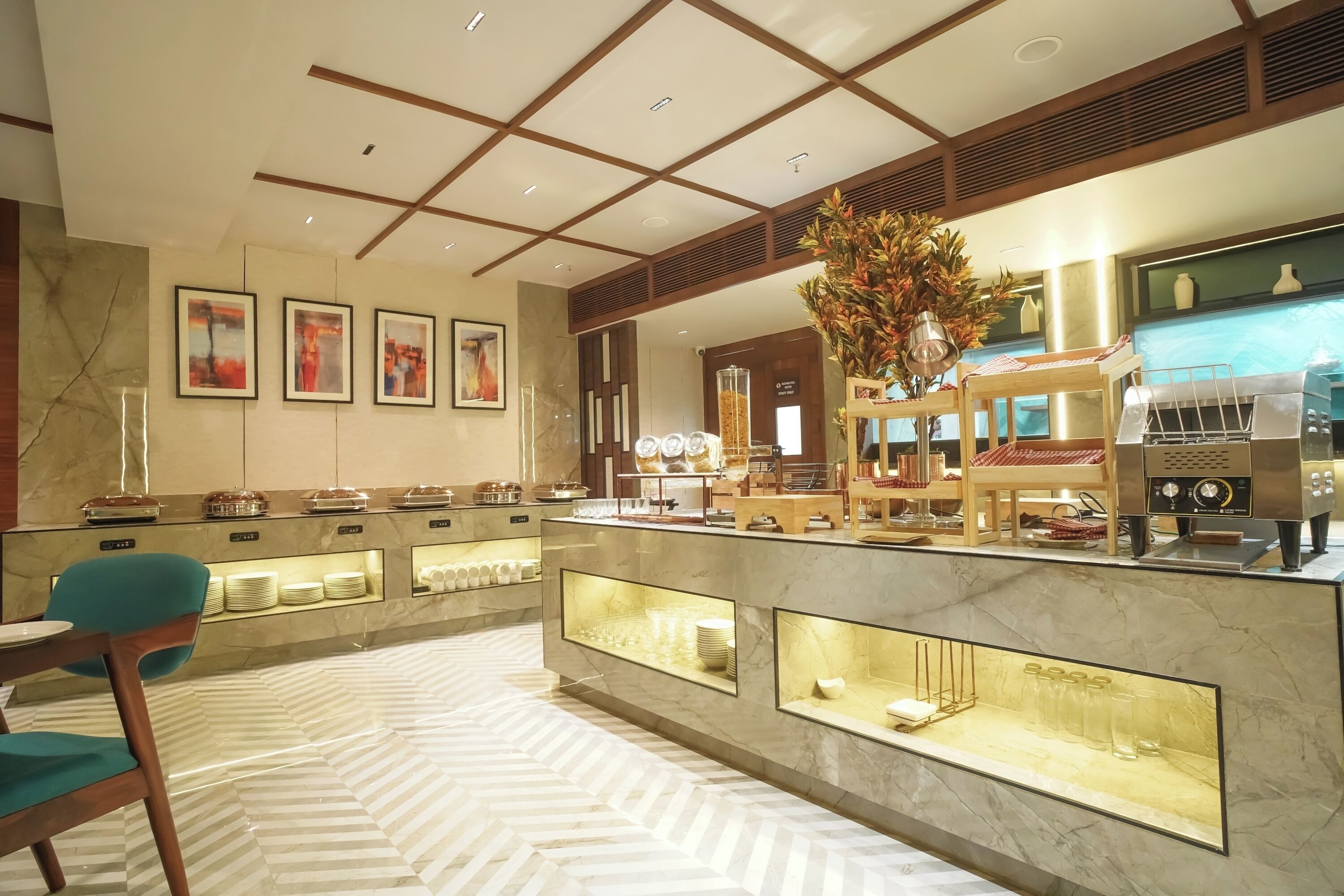 Un hall d’hôtel moderne avec un comptoir d’accueil en marbre, une machine à café et un espace détente doté d’un sol à motifs.