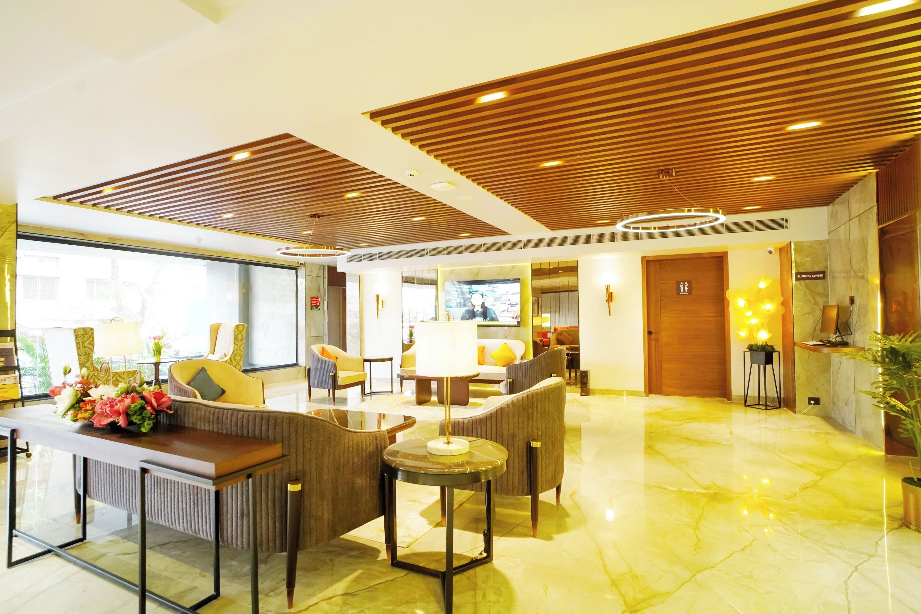 A spacious lobby with a wooden ceiling, comfortable seating, a reception desk, and a marble floor.