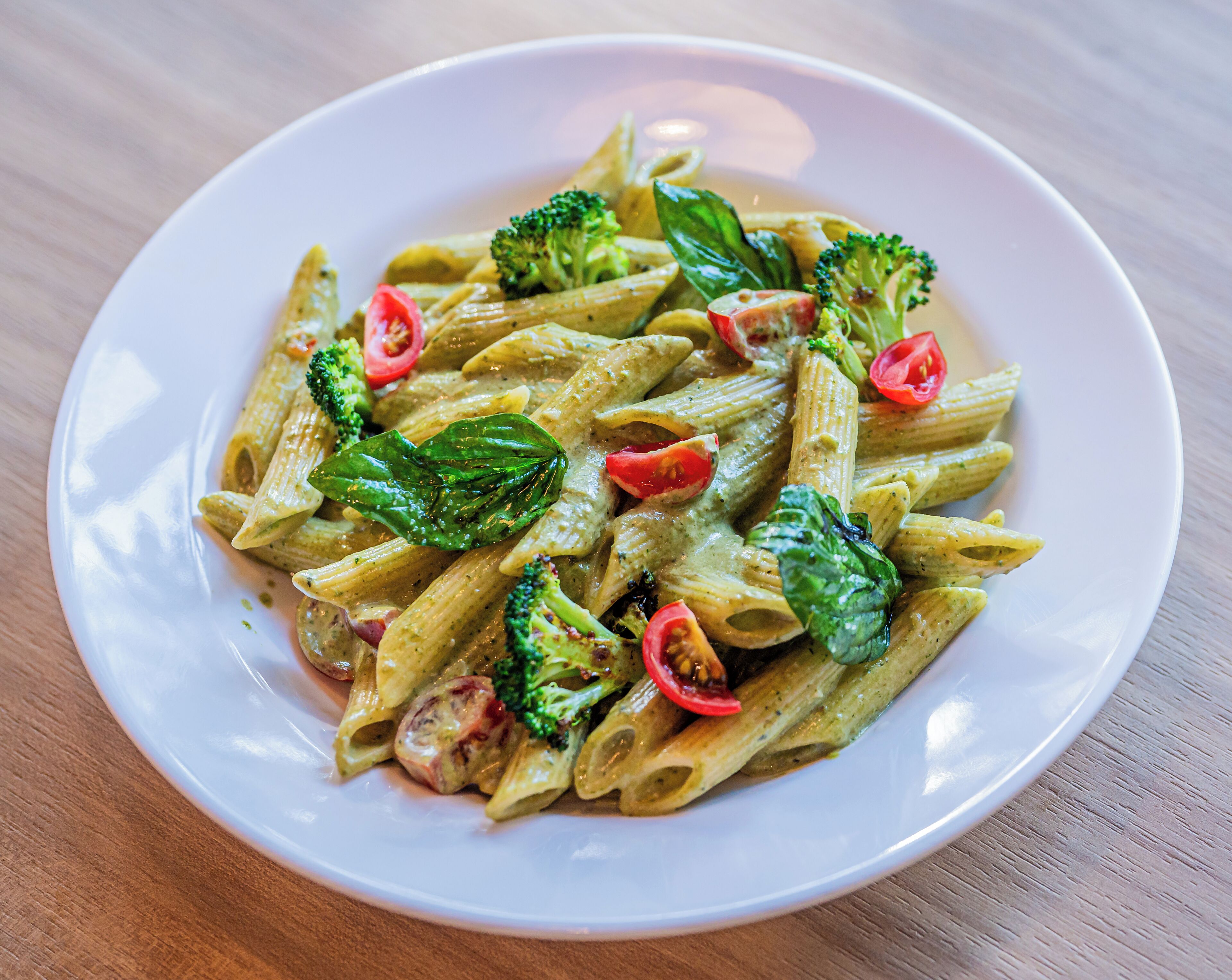 A plate of pasta with broccoli and tomato slices.