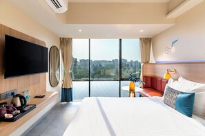 Ein modernes Hotelzimmer mit einem großen Bett, einem Flachbildfernseher, einer Sitzecke und Blick auf die Stadt.