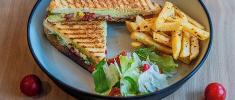 A plate with a grilled sandwich, French fries, and a side salad.