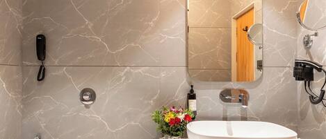 A modern bathroom with a marble floor, a white toilet, a sink with a mirror, and a shower area.