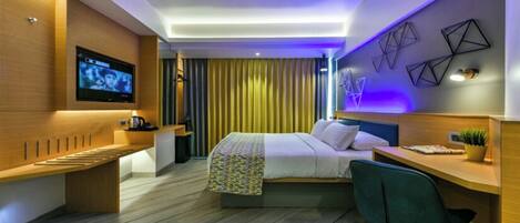 Een moderne hotelkamer met een bed, bureau en zithoek.