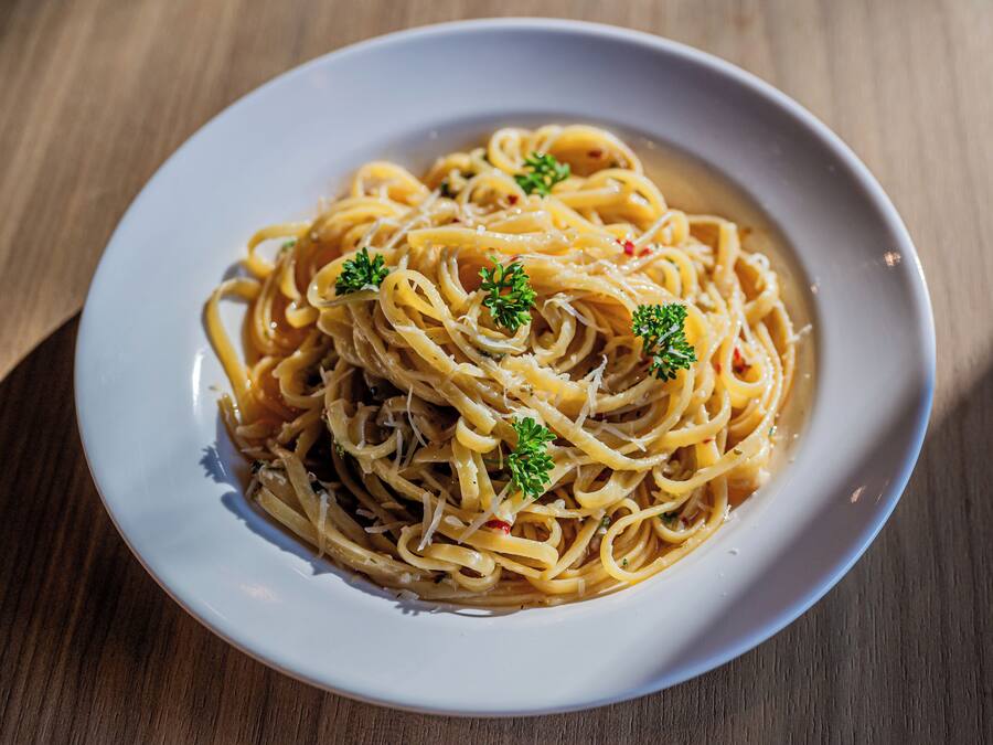 A plate of spaghetti with a garnish of parsley, served on a white plate.
