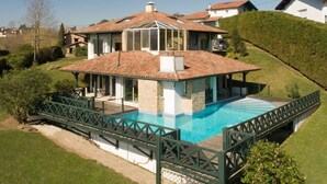 A house with a swimming pool, a covered patio, and a green fence. - Architect-designed house with swimming pool 10 minutes from St Jean de Luz (Urrugne)