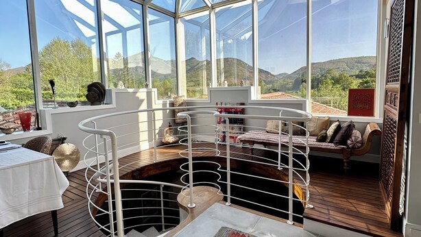 A spacious room with a large glass ceiling, a wooden ceiling, a dining table, a bench, and a view of the outdoors. - Architect-designed house with swimming pool 10 minutes from St Jean de Luz (Urrugne)