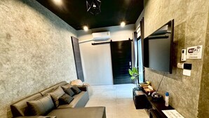 Un salon moderne avec un canapé, un téléviseur à écran plat, une console et un panneau indiquant la présence d’une connexion Wi-Fi.