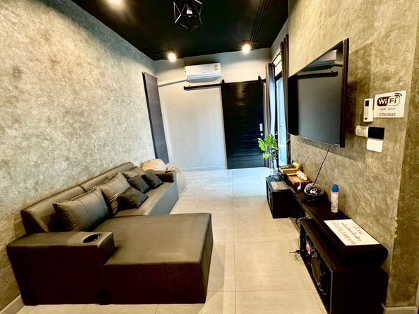 A modern living room with a sofa, a flat-screen TV, a console table, and a Wi-Fi sign. - Happy pool villa (Hua Hin)