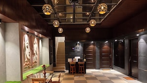 A modern interior with a checkered floor, wooden furniture, and geometric pendant lighting. - Sun Rays Inn (Yercaud)