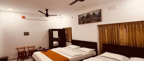 A hotel room with two beds, a desk, a chair, a ceiling fan, and a painting on the wall.