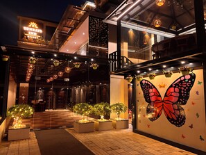 A hotel entrance with a large butterfly mural, outdoor seating, and a checkered floor. - Sun Rays Inn (Yercaud)