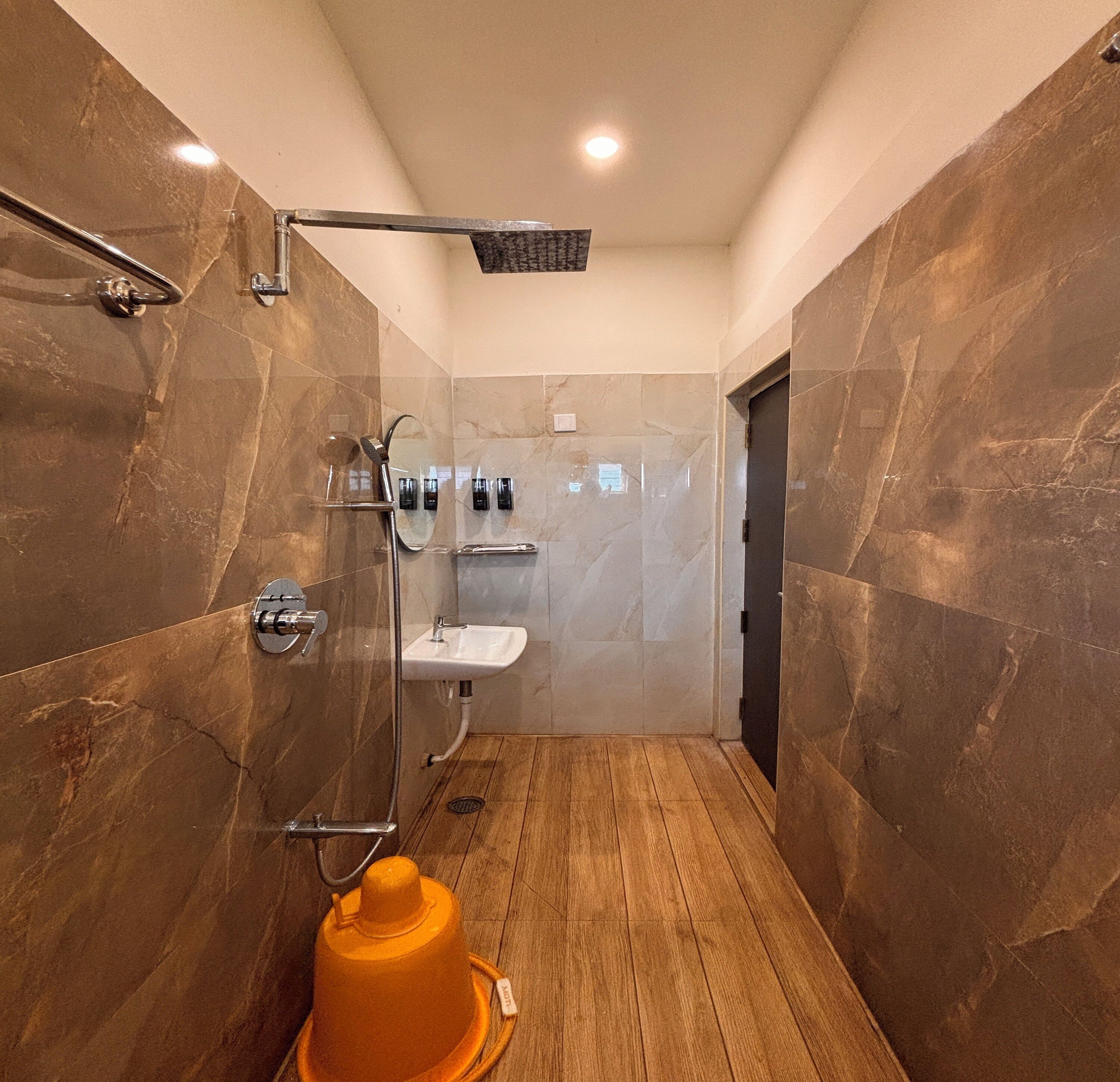 Un baño moderno con ducha de vidrio, suelo de madera e lavamanos.