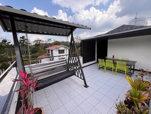 A rooftop terrace with a swing, a dining table with chairs, and potted plants. - Sun Rays Inn (Yercaud)