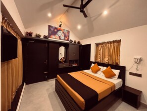 A bedroom with a bed, a ceiling fan, a TV, a mirror, a window with curtains, and a wall-mounted phone. - Sun Rays Inn (Yercaud)