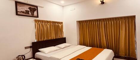 A hotel room with a bed, a nightstand, a ceiling fan, a wall-mounted light, and a window with curtains.